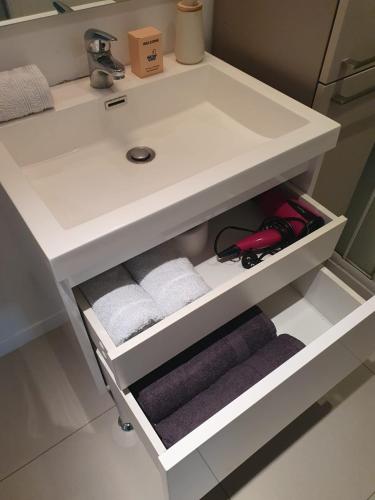 - un lavabo blanc dans la salle de bains avec serviettes sur une étagère dans l'établissement Appartement cosy et calme, à Nantes