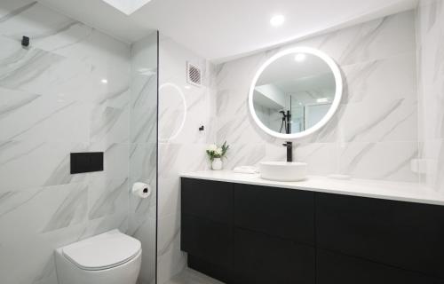 a white bathroom with a toilet and a mirror at Seaview Resort in Mooloolaba
