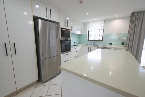 a kitchen with white cabinets and a stainless steel refrigerator at Seaview Resort in Mooloolaba