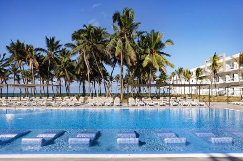 una piscina con tumbonas y palmeras en Riu Turquoise - All Inclusive en Le Morne