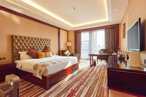 a hotel room with a bed and a flat screen tv at Wyndham Grand Plaza Royale Chenzhou in Chenzhou