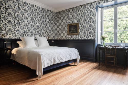 a bedroom with a bed and a window and a desk at Château Sénéjac in Le Pian-Médoc