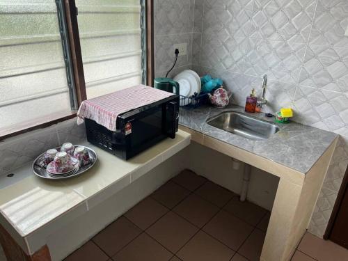 カジャンにあるHarith's Little Homestayのシンクと食器が置かれたキッチンカウンター