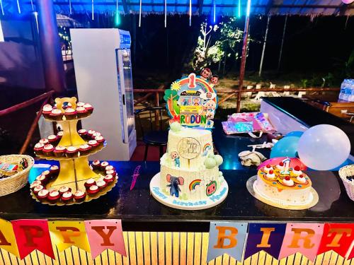 a table topped with a birthday cake and balloons at The Windchimes Retreat Coorg in Virajpet