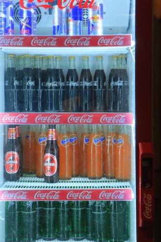 a refrigerator filled with bottles of cocacola soda at Hotel Diamond in Bharatpur