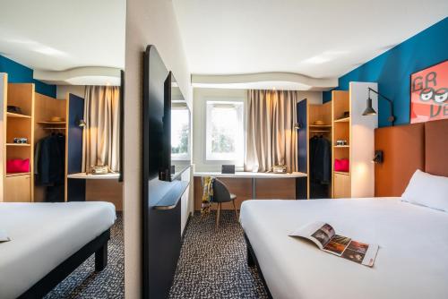 a hotel room with two beds and a desk at ibis Chalon Sur Saone Nord in Chalon-sur-Sa&ocirc;ne