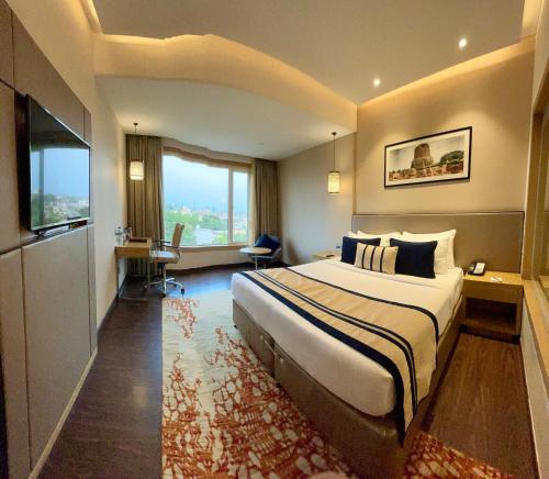a hotel room with a large bed and a desk at The Fern Residency Sarnath in Varanasi