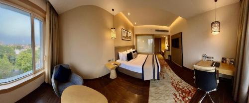 a hotel room with a bed and a large window at The Fern Residency Sarnath in Varanasi