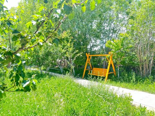 a yellow swing in the middle of a field of grass at Eco Resort Kaiyrma in Bokonbayevo