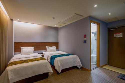 two beds in a room with a bathroom at Namsan Hill Hotel in Seoul