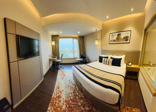 a hotel room with a large bed and a flat screen tv at The Fern Residency Sarnath in Varanasi