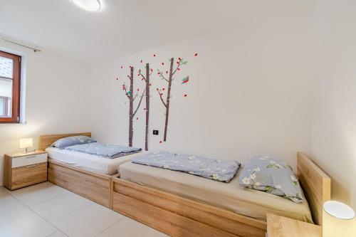 two beds in a room with trees on the wall at Penzion Hosnar, hiša Mišc in Bovec