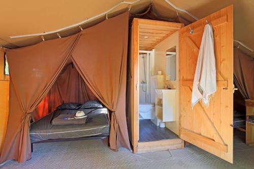 - une chambre avec un lit à l'intérieur d'une tente dans l'établissement Huttopia Royat, à Royat