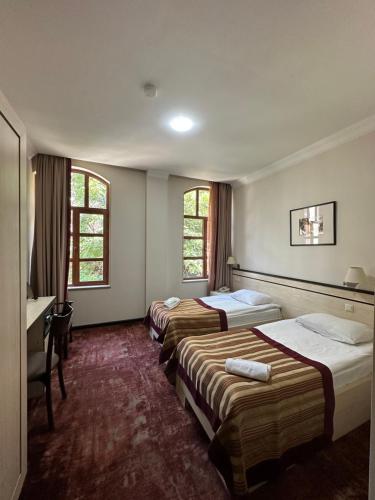 Habitación de hotel con 3 camas y escritorio. en Hotel Europe plaza en Tiflis