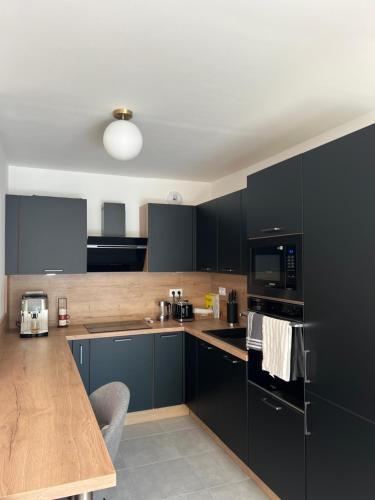 une cuisine avec des armoires noires et un comptoir en bois dans l'établissement Brand new flat near Paris and public transports, à Le Perreux-Sur-Marne