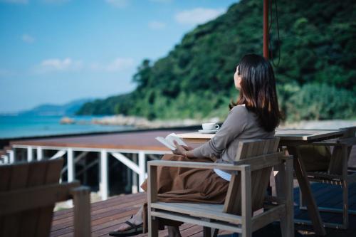 a woman sitting at a table reading a book at Colorit GOTO ISLANDS in Goto