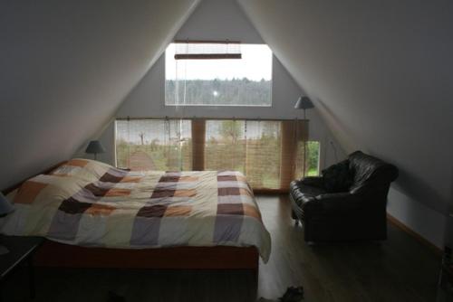 a bedroom with a bed and a chair and a window at Dom letniskowy ORCHIDEA in Chrzanowo