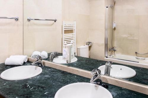 een badkamer met 2 wastafels en een spiegel bij B&B HOTEL Madrid Aeropuerto T4 in San Sebastián de los Reyes