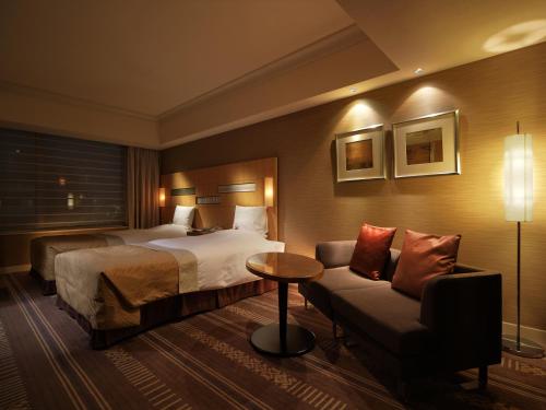 a hotel room with a bed and a couch at Hotel Okura Fukuoka in Fukuoka