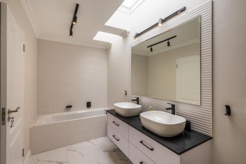 Un baño con dos lavabos, una bañera y un espejo. en Sun Centre 9, en Plettenberg Bay
