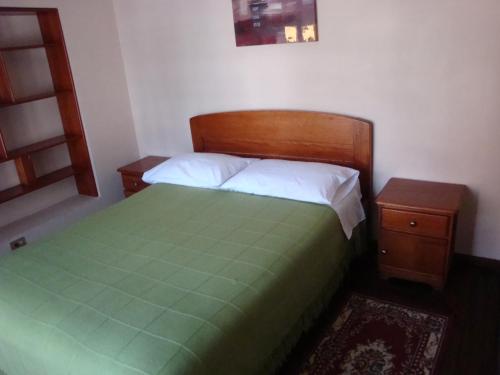 a bedroom with a green bed and two night stands at Hostal Santa María Gracia in Quito