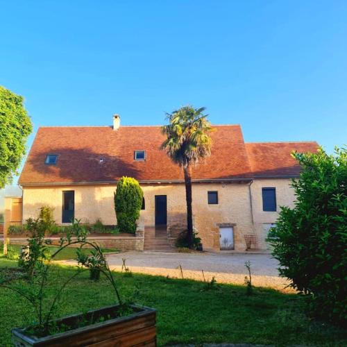 une grande maison avec un palmier en face dans l'établissement Gite Nature 24 entre Lascaux et Sarlat, à Saint-Geniès