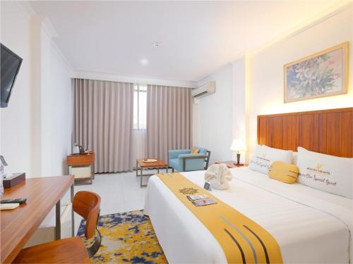 Habitación de hotel con cama grande y escritorio. en Metro Park View Hotel Kota Lama Semarang, en Semarang