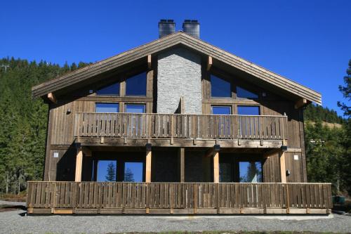 a large wooden house with a balcony at Sjusjøen Hytteutleie AS in Sjusjøen