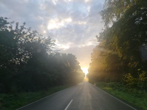 an empty road with the sun setting in the distance at Hus Meeresbrise in Arrild