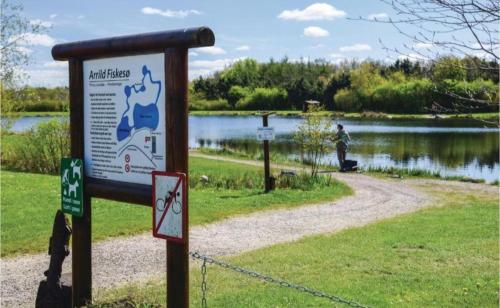 a sign in front of a lake with a person in the background at Hus Meeresbrise in Arrild