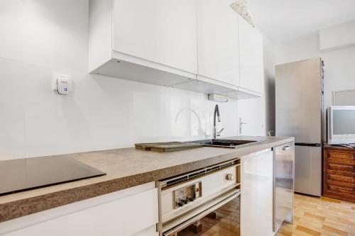 une cuisine avec des armoires blanches et un comptoir dans l'établissement Vue mer dans les collines Cavalaire, à Cavalaire-sur-Mer