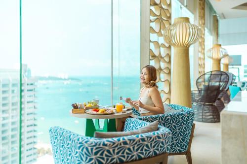 a woman sitting at a table with a plate of food at Holiday Inn Pattaya by IHG in Pattaya Central