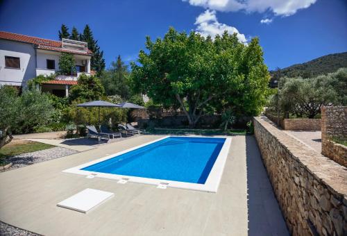 a swimming pool in front of a house at Jees Exclusive Apartments Hvar in Stari Grad