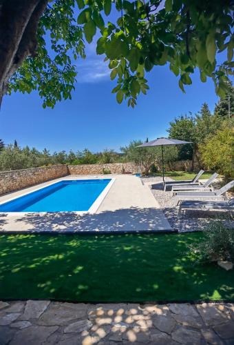 a swimming pool with a table and an umbrella at Jees Exclusive Apartments Hvar in Stari Grad