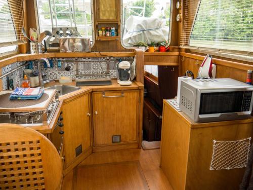 - une petite cuisine avec des placards en bois et un four micro-ondes dans l'établissement Spicy - Séjour insolite sur la Marne, à Meaux