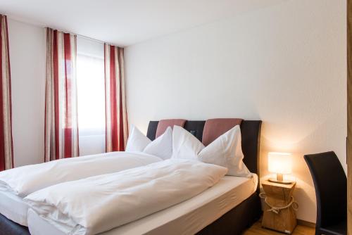 a bedroom with a bed with white sheets and a window at Titlis Resort in Engelberg