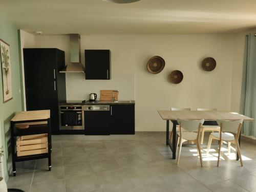 une cuisine avec des armoires noires, une table et des chaises dans l'établissement T2 Charme, intramuros, quartier des Teinturiers, à Avignon