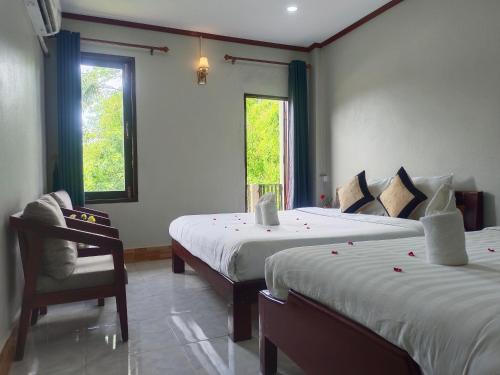 Dokchampa Hotel في فانغ فينغ: غرفة نوم بسريرين وكرسي ونوافذ