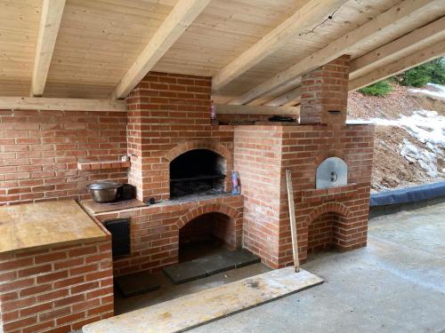 an outdoor brick oven with a wooden roof at A Frame Pietrele Șoimului in Cavnic