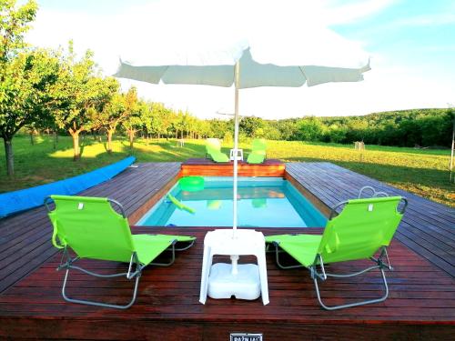 a deck with a pool and two chairs and an umbrella at Sunny Side Fruska Gora- apartman A in Velika Remeta