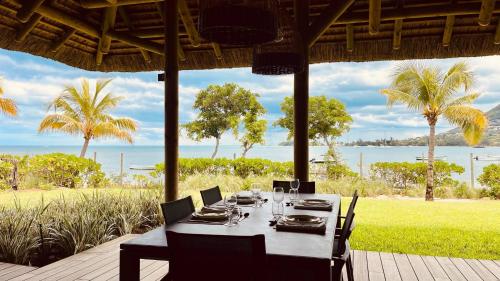 a dining table on a patio with a view of the ocean at Villa de luxe La Paillotte in Petite Case Noyale