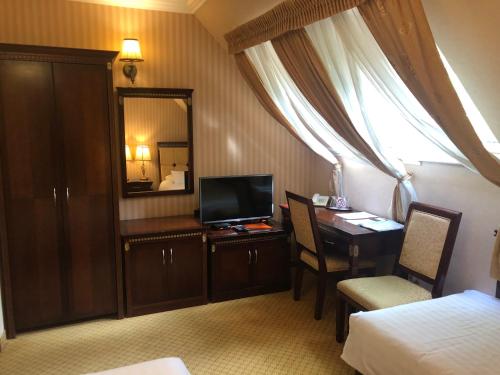 a hotel room with a desk and a bed and a mirror at Villa Hotel in Debrecen