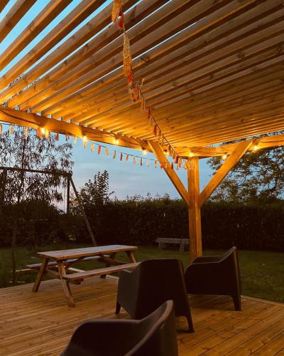 une pergola en bois avec une table de pique-nique et des chaises dans l'établissement La Passerelle, à Morlaix