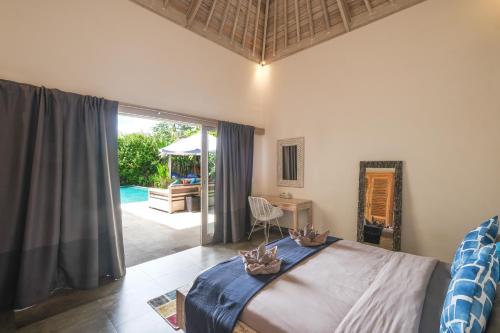 a bedroom with a bed and a view of a pool at Villa Alexandra Bingin in Uluwatu