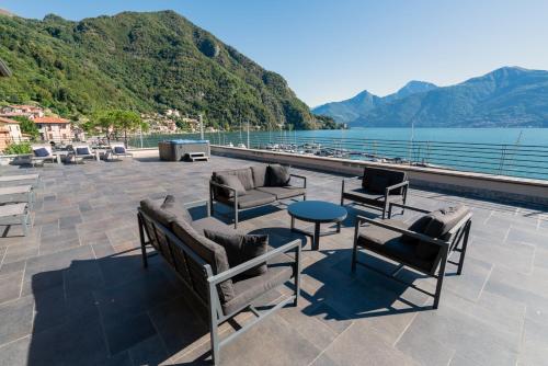 eine Terrasse mit Stühlen und Tischen und Blick auf das Wasser in der Unterkunft Villa Navalia in Menaggio