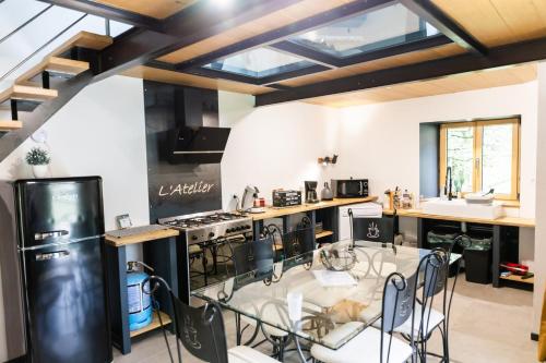 une cuisine avec des appareils en noir et blanc et une table en verre dans l'établissement Gîte de caractère à la campagne, à Fercé