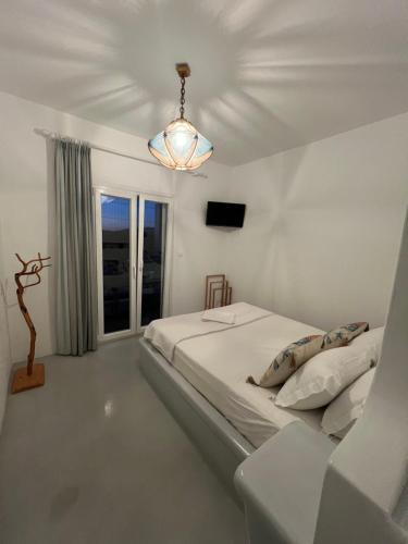 a white bedroom with a bed and a chandelier at Alexandra’s studios in Iraklia