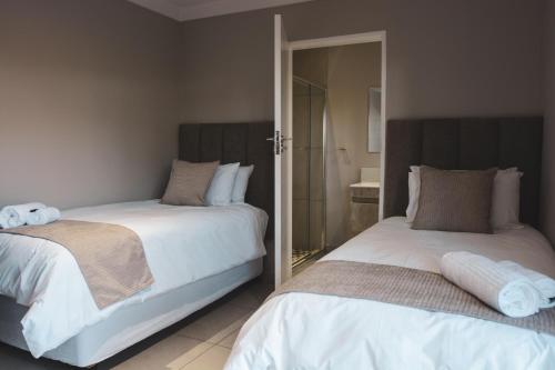 two beds sitting next to each other in a bedroom at Palmera Guest House in Krugersdorp