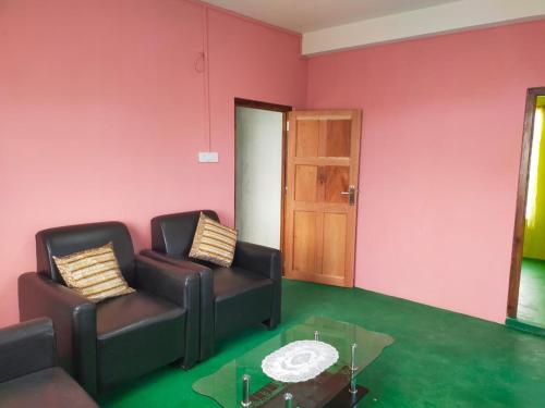 a living room with two chairs and a glass table at itynnad homestay in Shillong