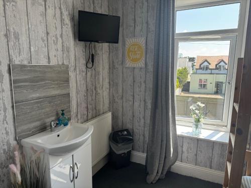 a bathroom with a sink and a television on the wall at Shore Lodge in Newquay